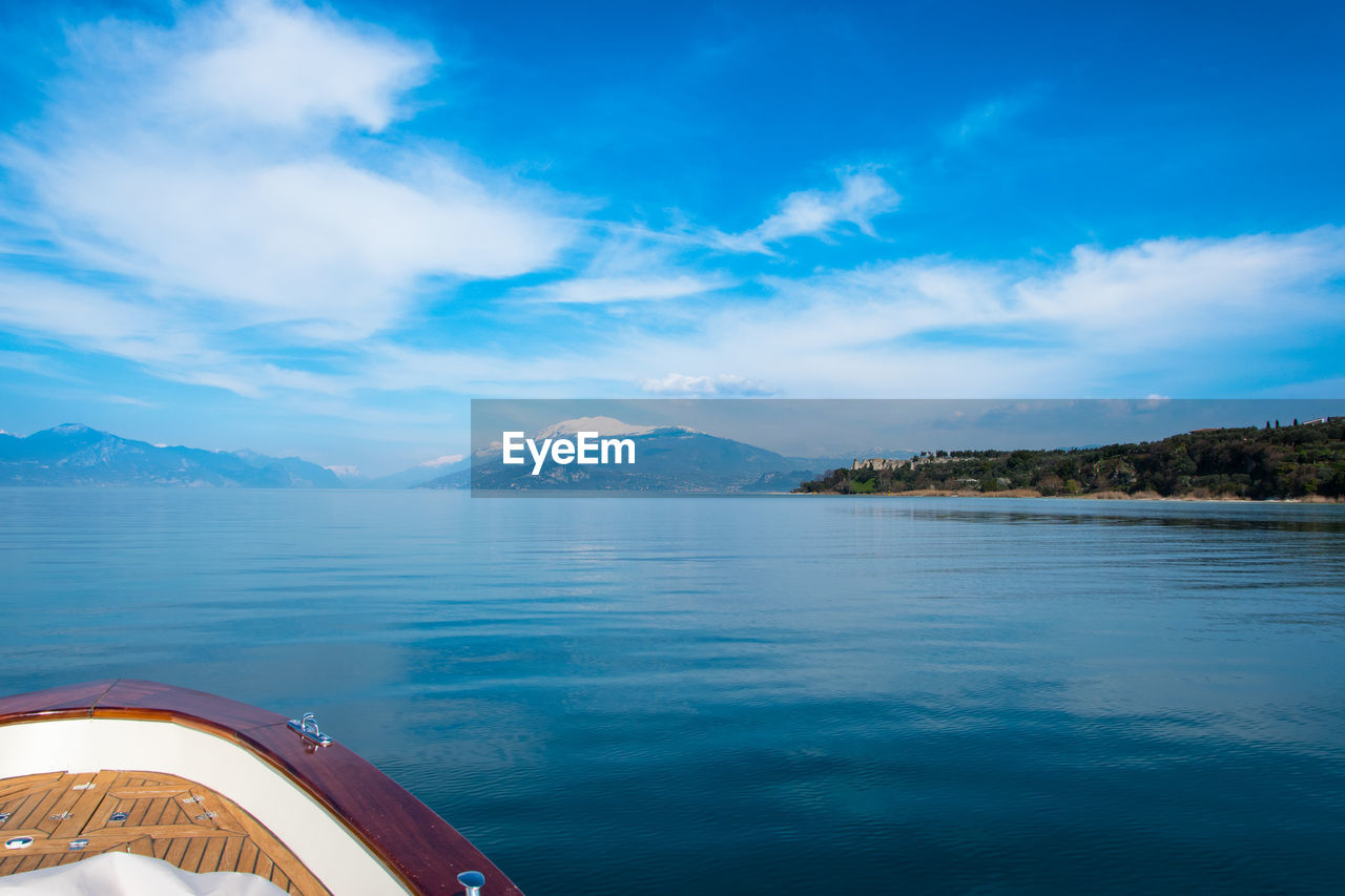 SCENIC VIEW OF SEA BY MOUNTAINS AGAINST BLUE SKY