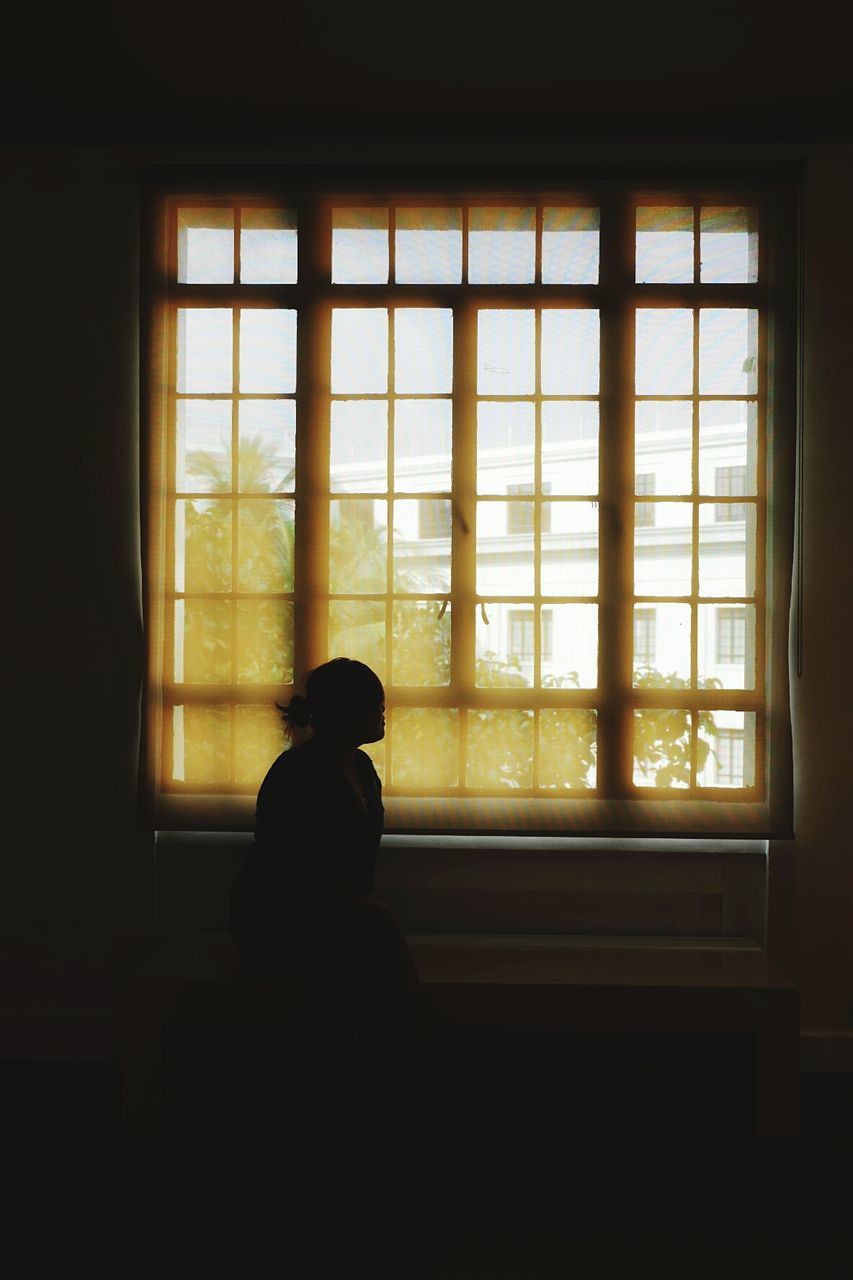 SILHOUETTE WOMAN LOOKING THROUGH WINDOW