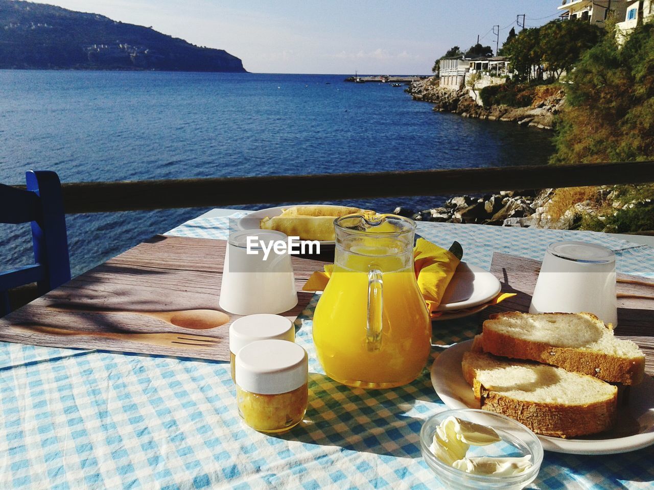 Orange juice with breakfast on table by sea