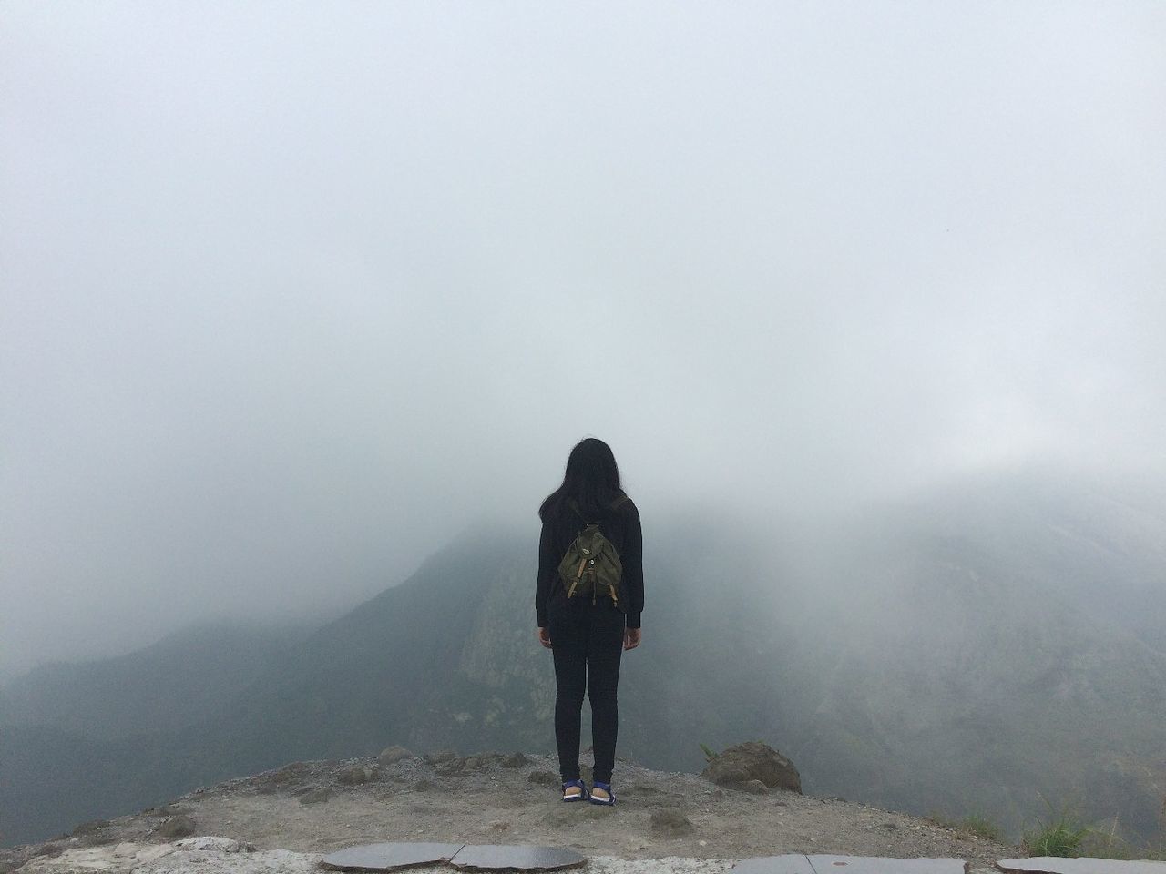 REAR VIEW OF WOMAN WALKING ON MOUNTAIN AGAINST SKY DURING FOGGY WEATHER