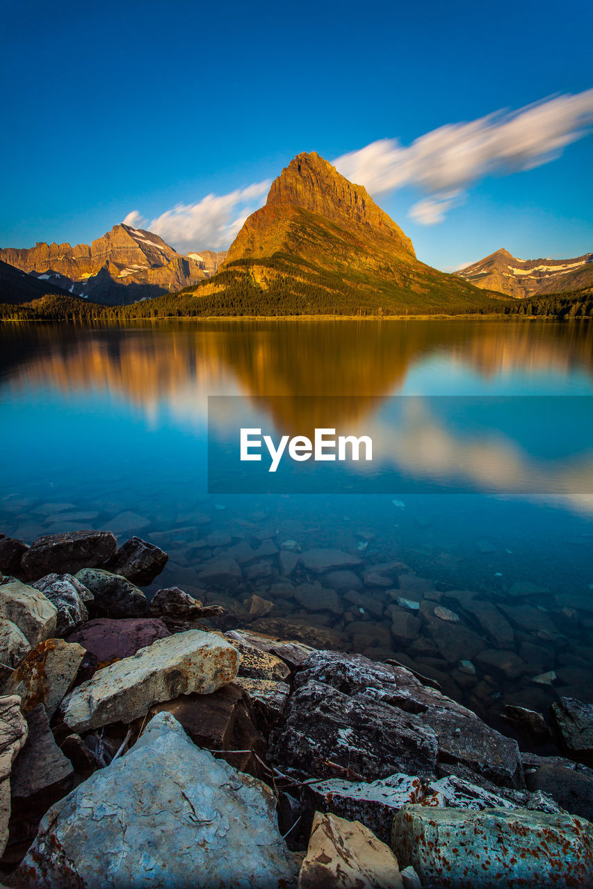 Scenic view of lake and mountains against blue sky