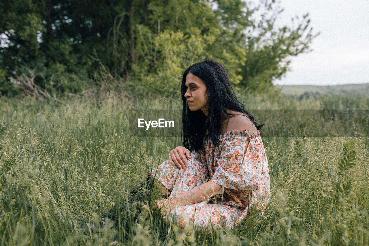 Portrait of woman alone in field thinking