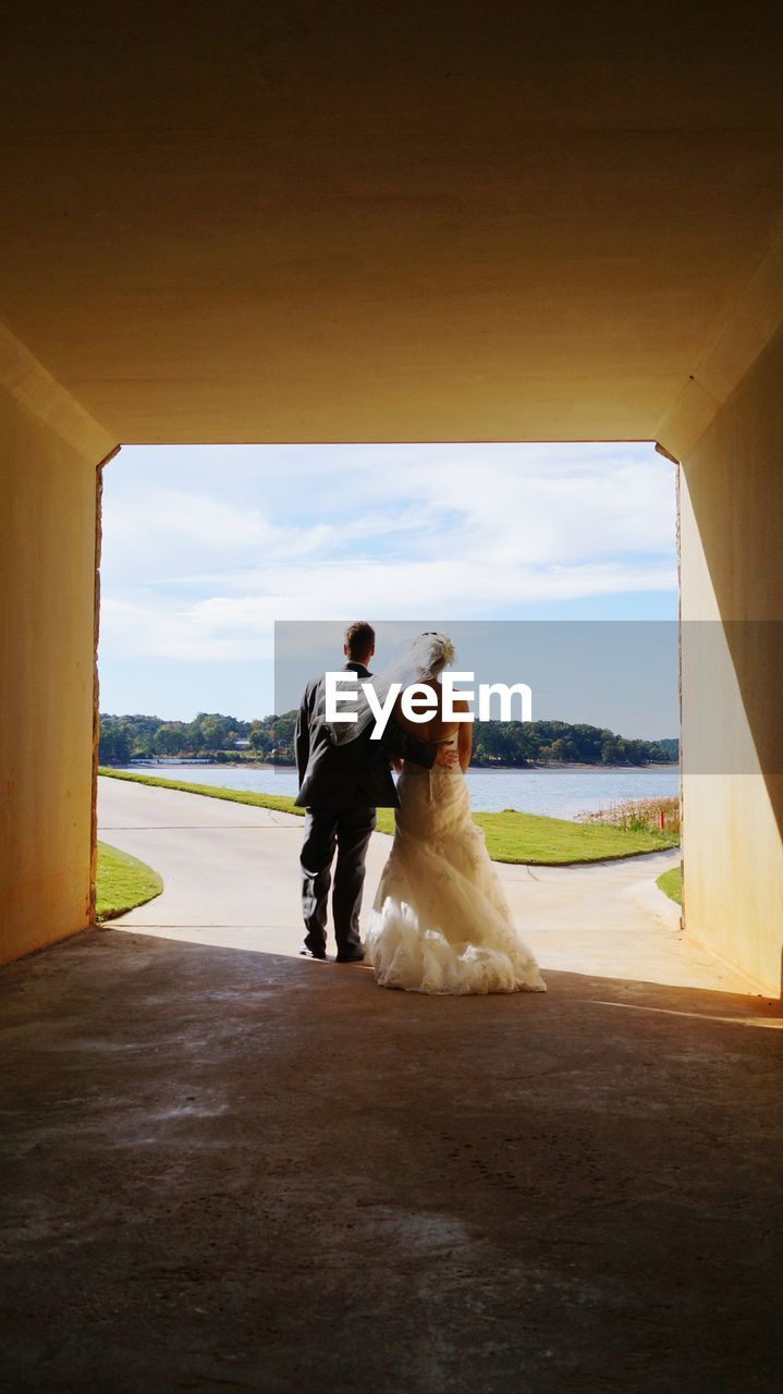 Rear view of wedding couple standing in tunnel