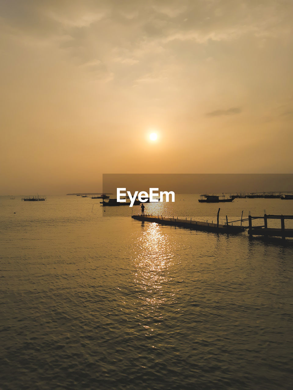 Scenic view of sea against sky during sunset with a silhouette of a man