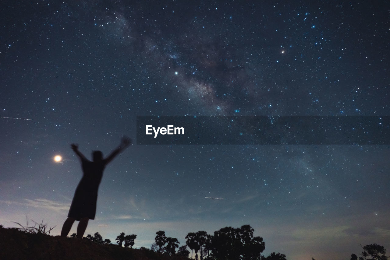 Low angle view of silhouette man standing against star field