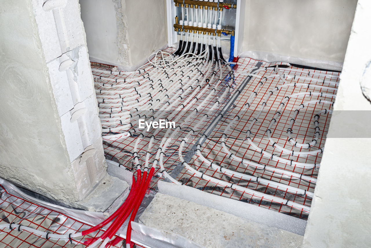 White pipes of underfloor heating systems, arranged in foil, passing through the foundation.