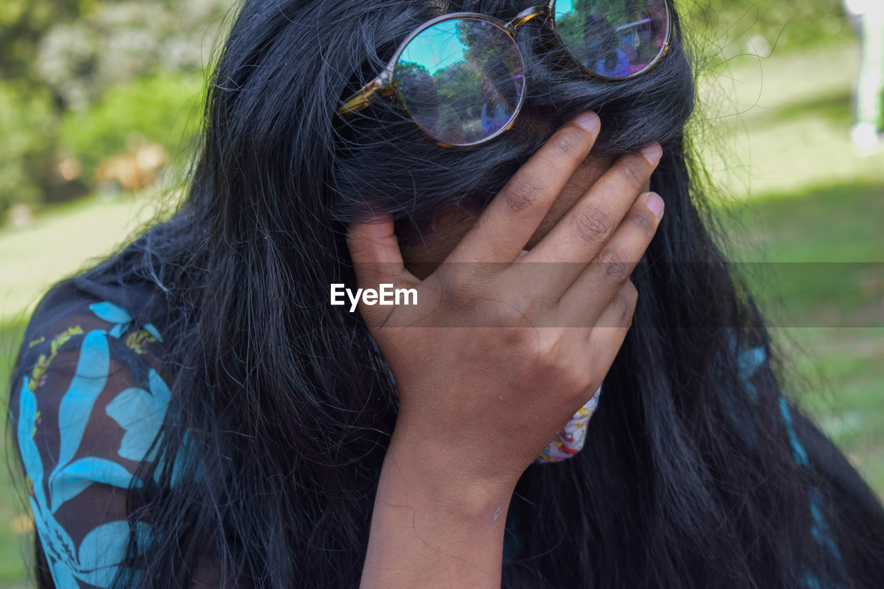 CLOSE-UP PORTRAIT OF WOMAN WITH HANDS ON HAIR