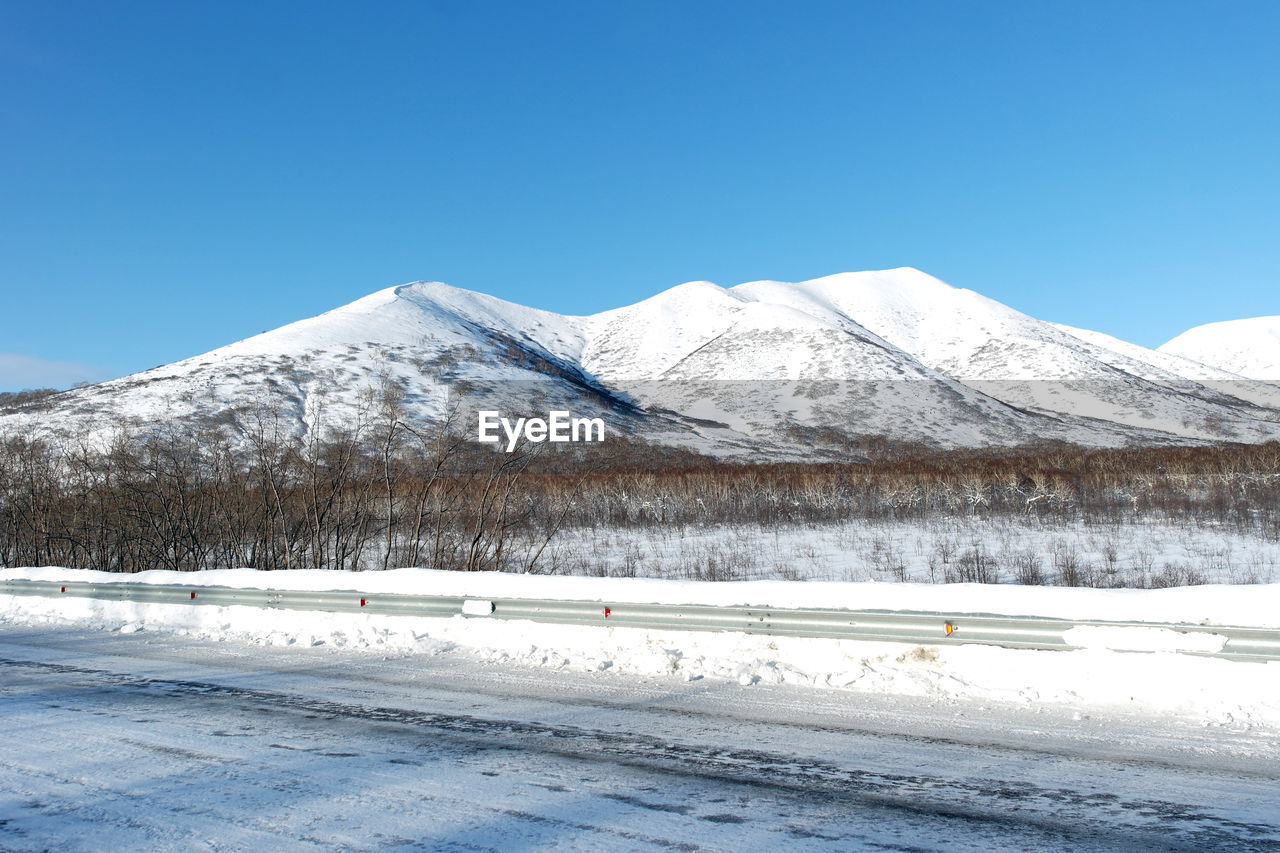 Scenic view of snowcapped mountains against clear blue sky