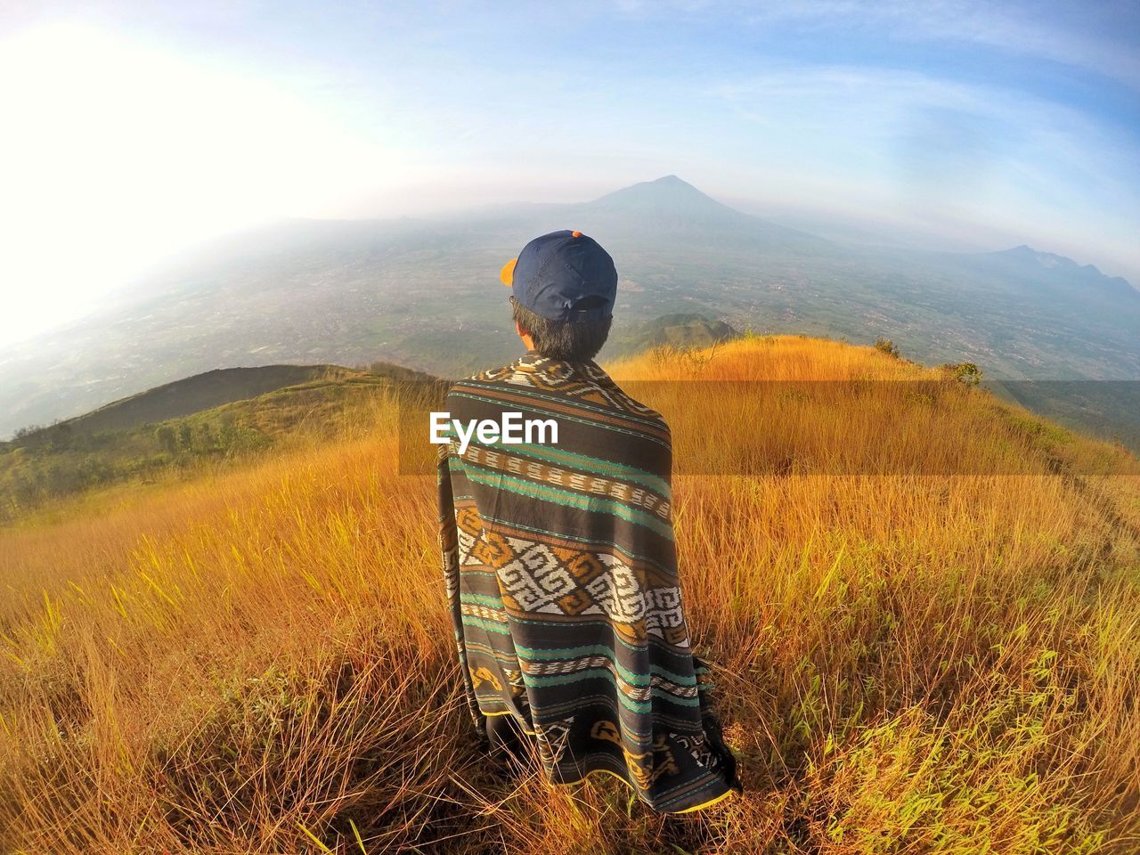 REAR VIEW OF MAN LOOKING AT VIEW OF MOUNTAIN