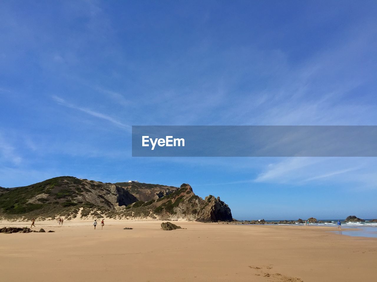 Scenic view of beach and rock formation against sky at praia do amado