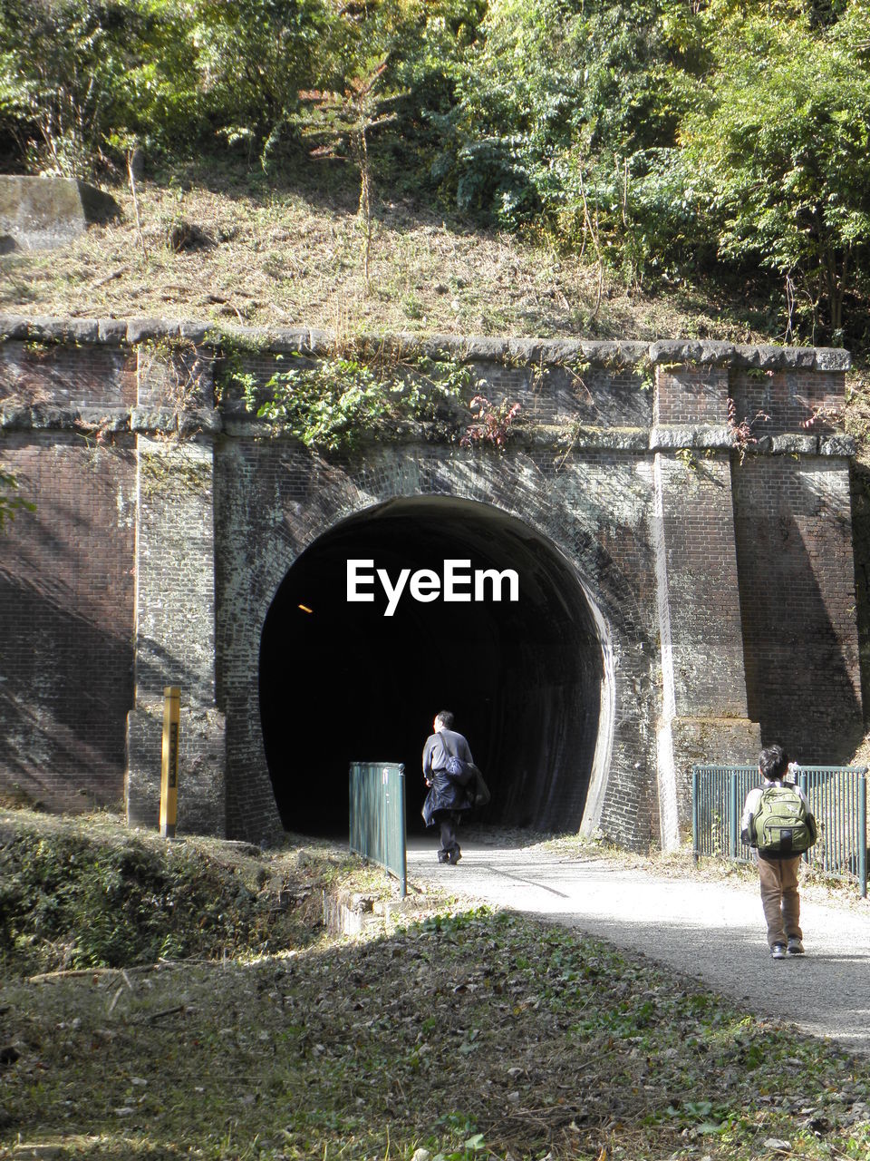 REAR VIEW OF MAN STANDING AT ARCH BRIDGE