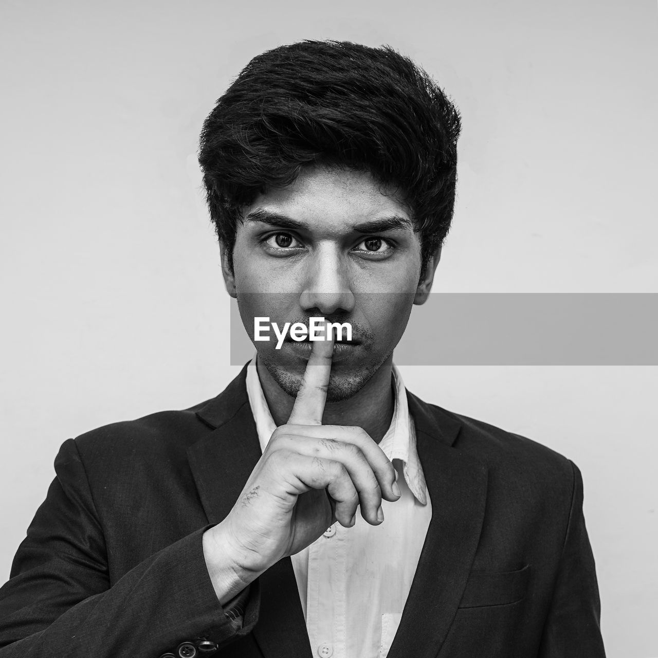 PORTRAIT OF YOUNG MAN AGAINST GRAY BACKGROUND