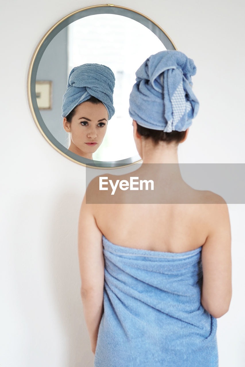 Reflection of woman on mirror in bathroom at home