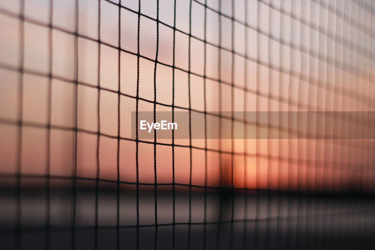 Full frame shot of metal fence against sky during sunset