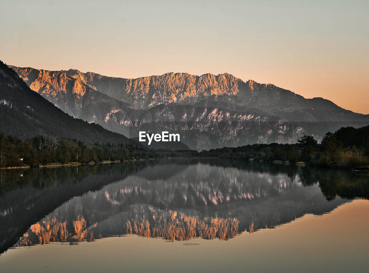 Scenic view of lake by mountains against sky during sunset