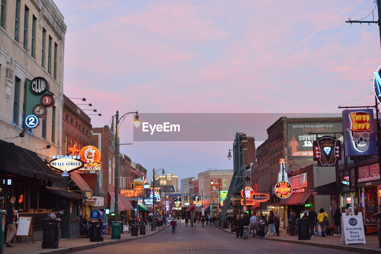 PEOPLE WALKING ON CITY STREET AT DUSK