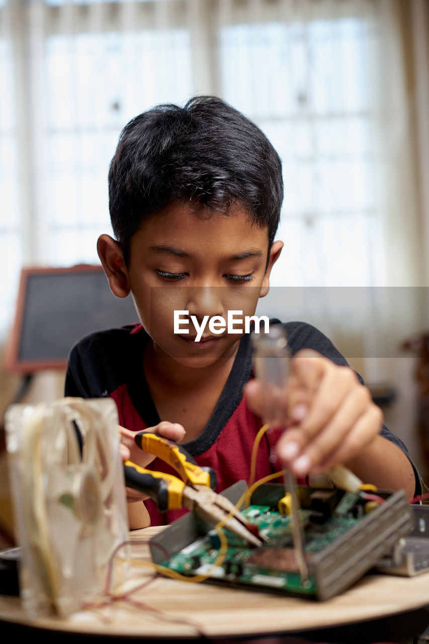 Asian schoolboy studying electronic at home