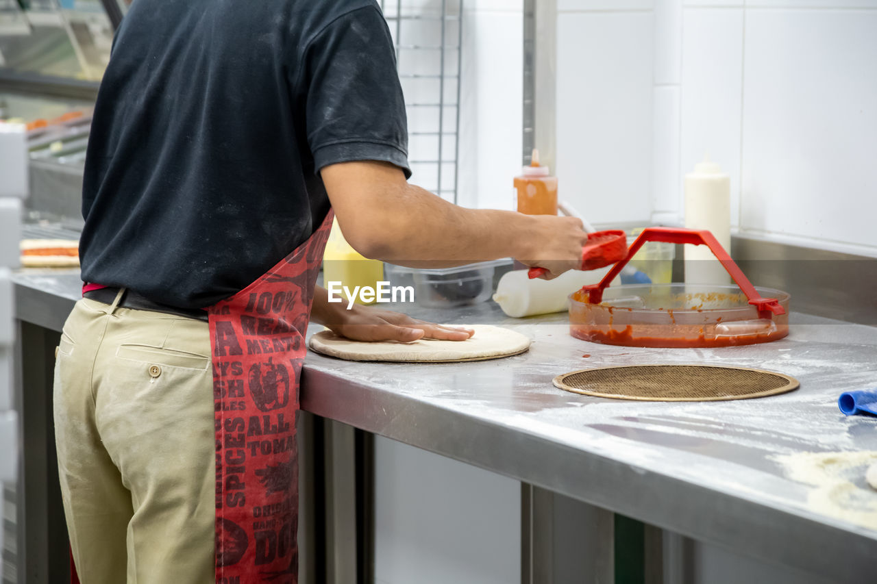 MIDSECTION OF MAN HAVING FOOD AT KITCHEN