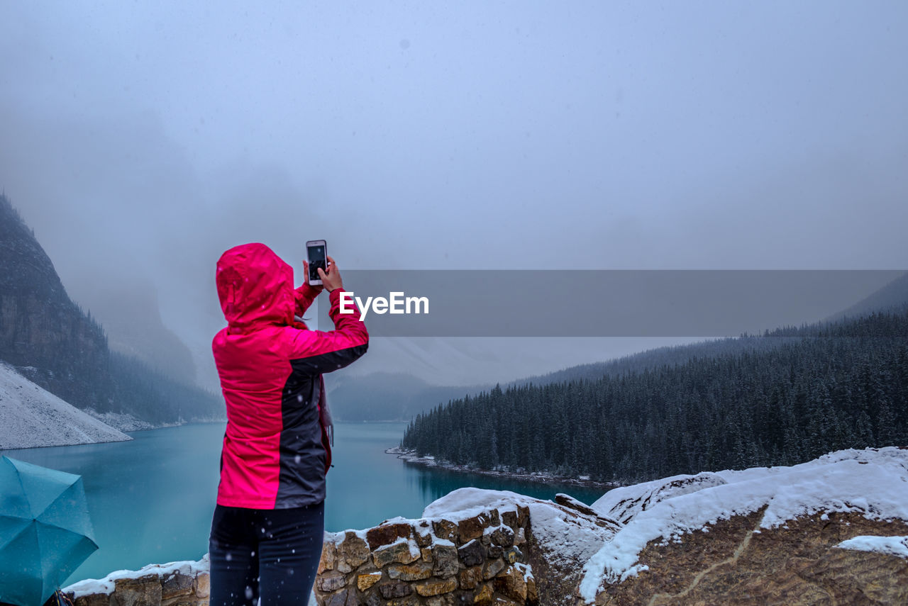 Rear view of woman photographing during winter