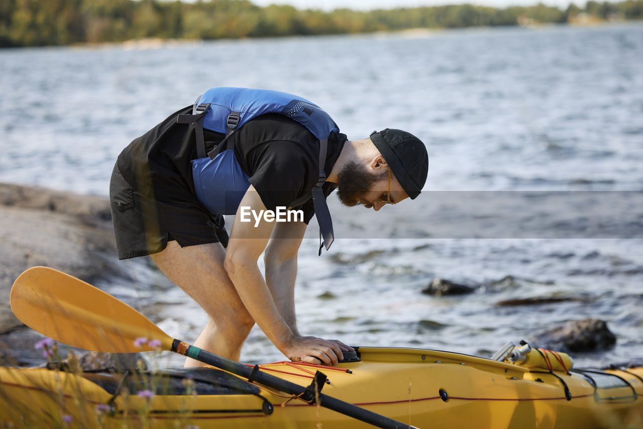 Man at sea standing near kayak