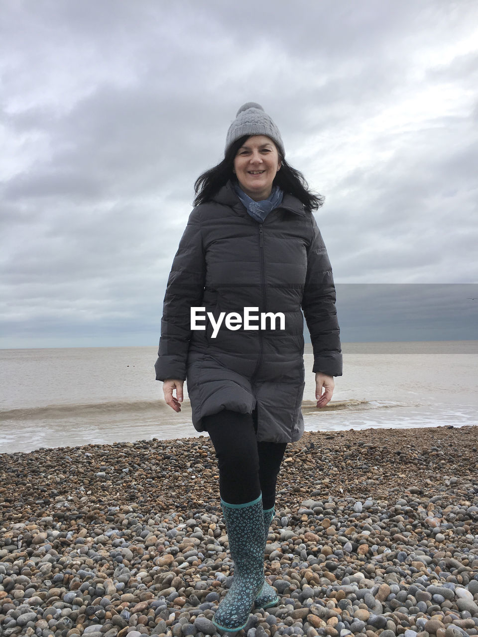 Happy woman walking towards camera on  beach