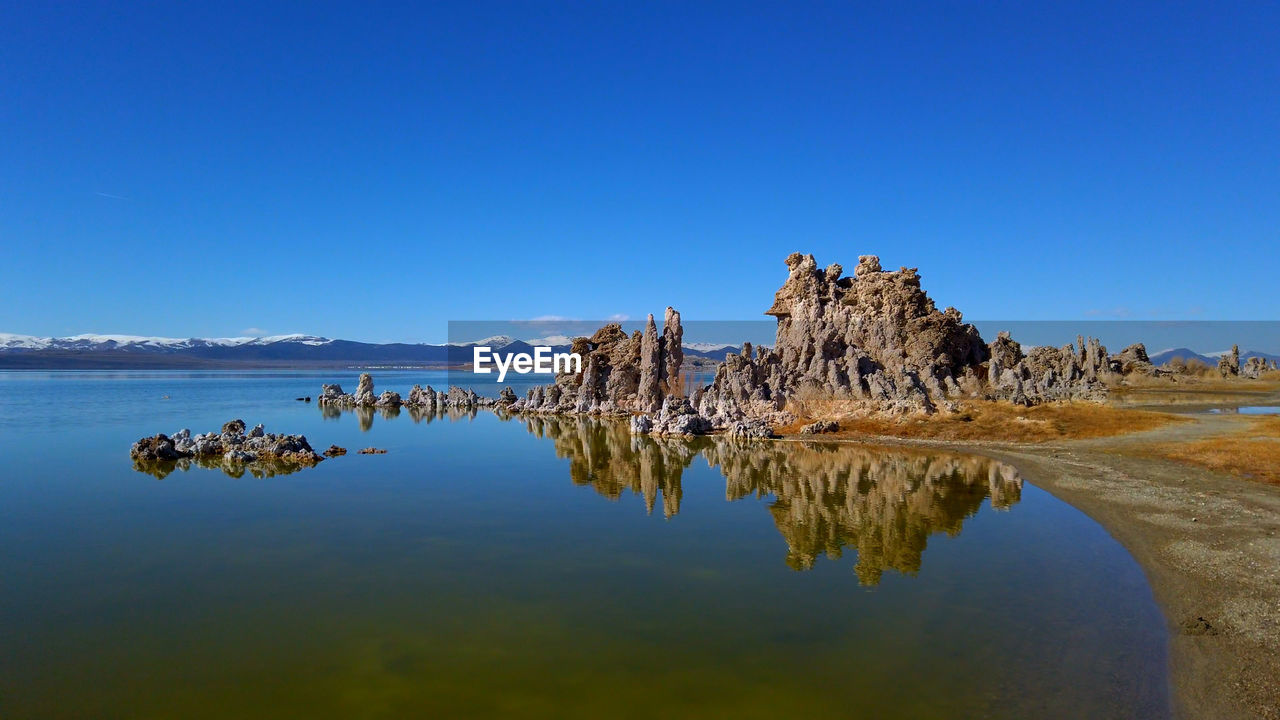 SCENIC VIEW OF ROCK FORMATION IN LAKE AGAINST CLEAR BLUE SKY