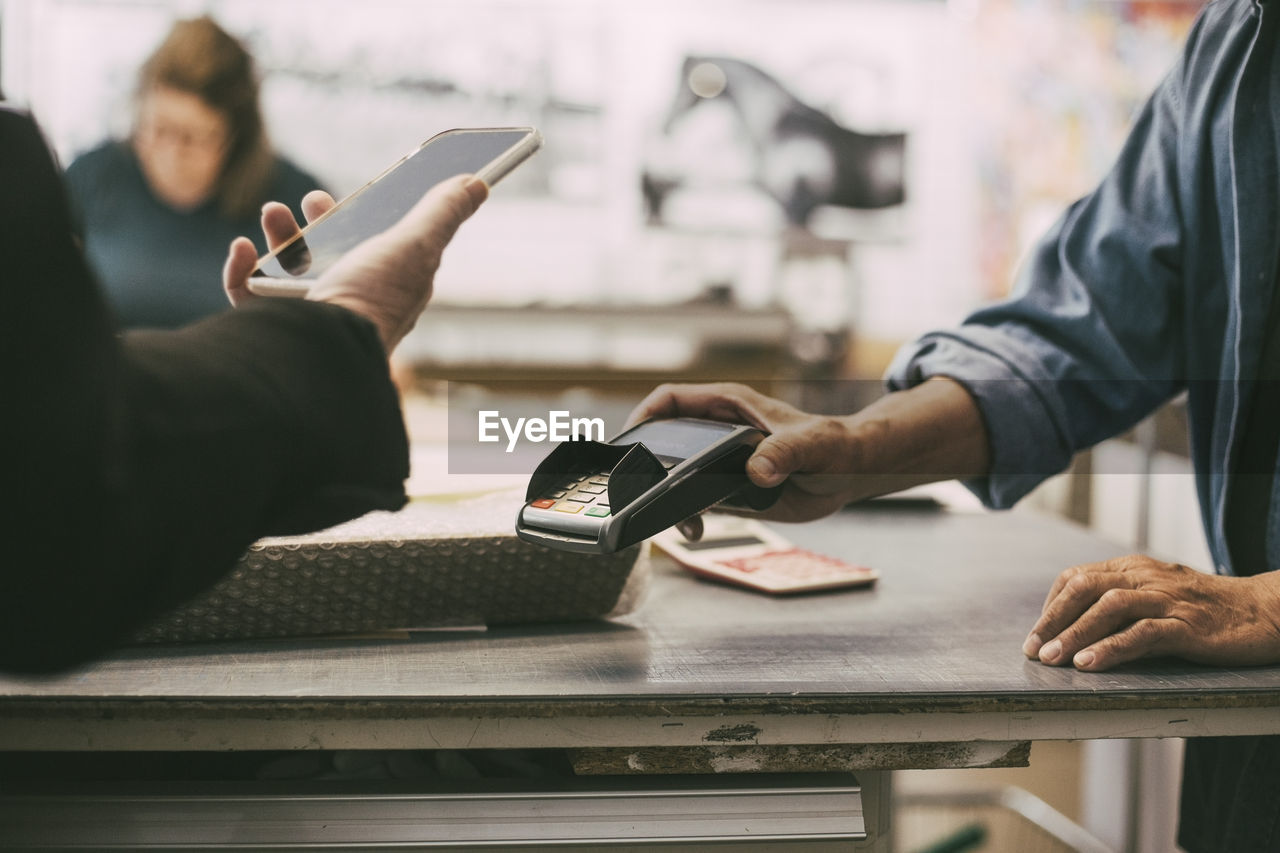 Cropped hand of female customer doing contactless payment at retail shop