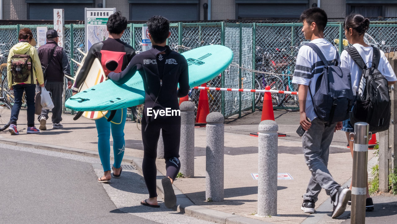 REAR VIEW OF PEOPLE WALKING ON STREET