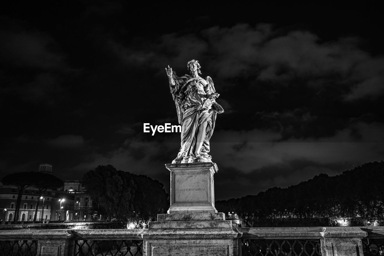 LOW ANGLE VIEW OF STATUE AGAINST CLOUDY SKY AT NIGHT