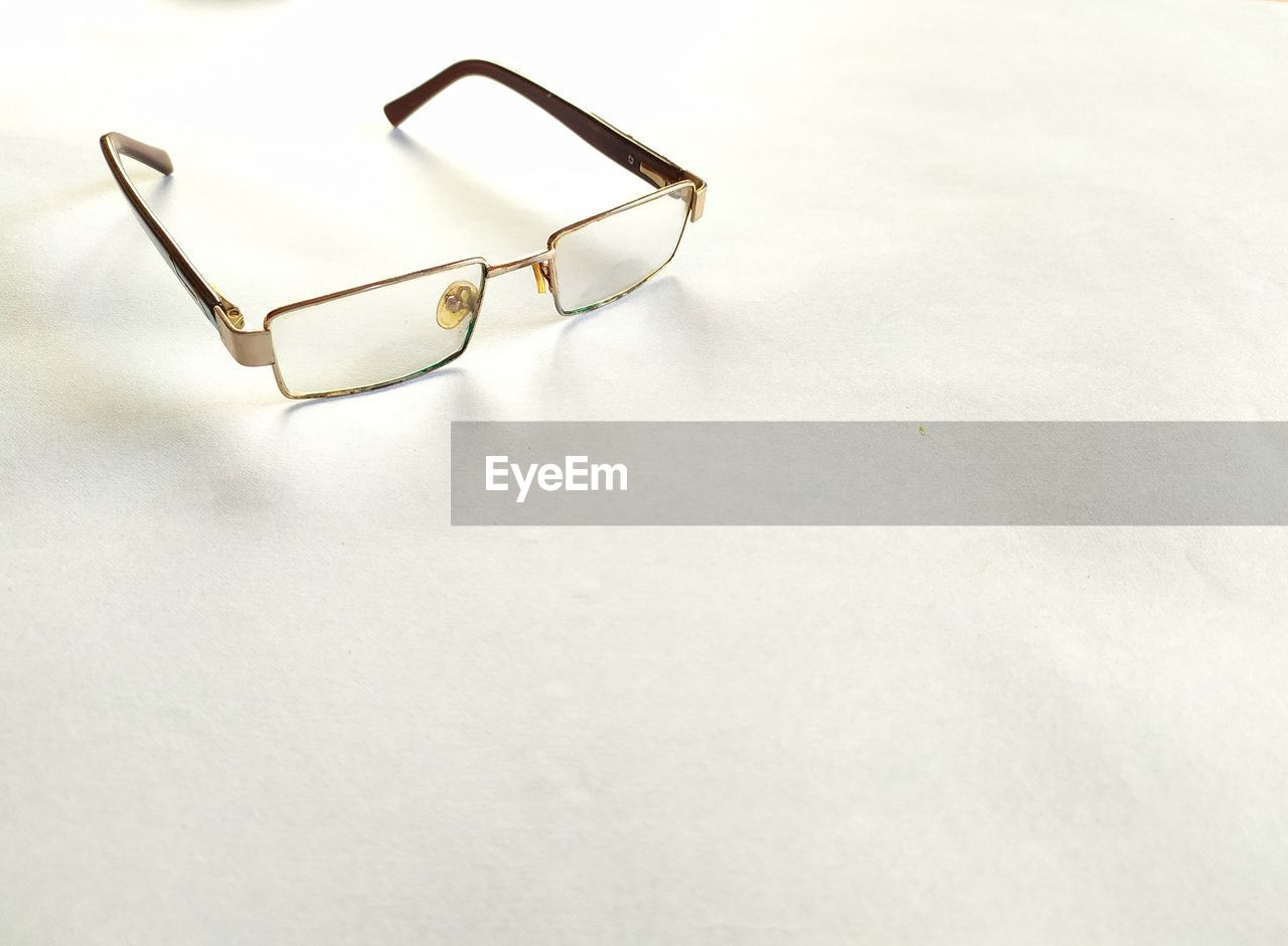 HIGH ANGLE VIEW OF EYEGLASSES ON GLASS TABLE