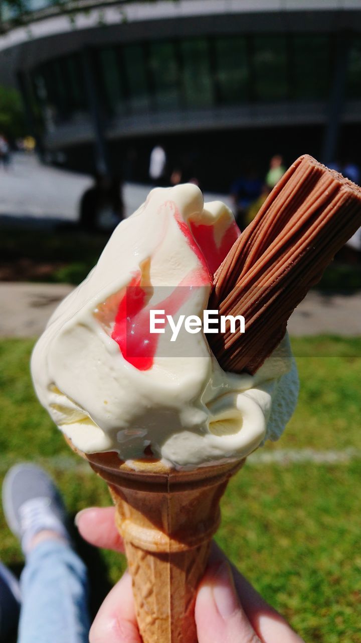 CLOSE-UP OF HAND HOLDING ICE CREAM