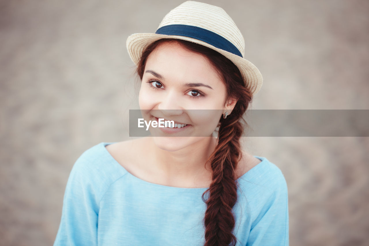 Close-up portrait of woman wearing hat at beach