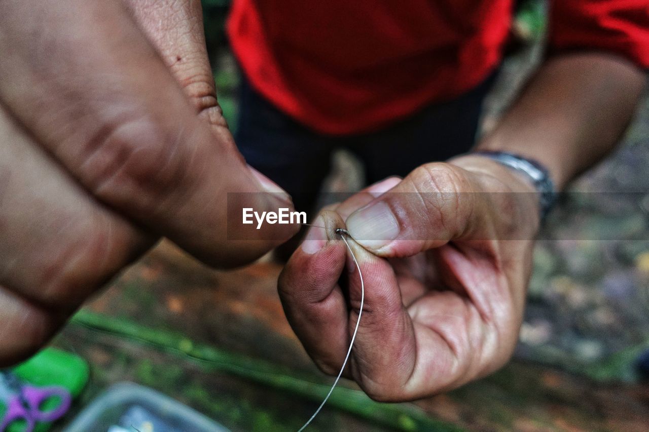 Low section of man preparing fishing tackle