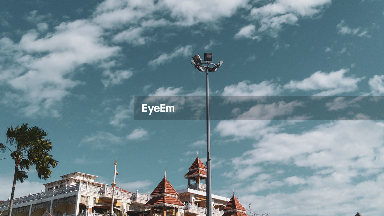 Low angle view of street light by building against sky