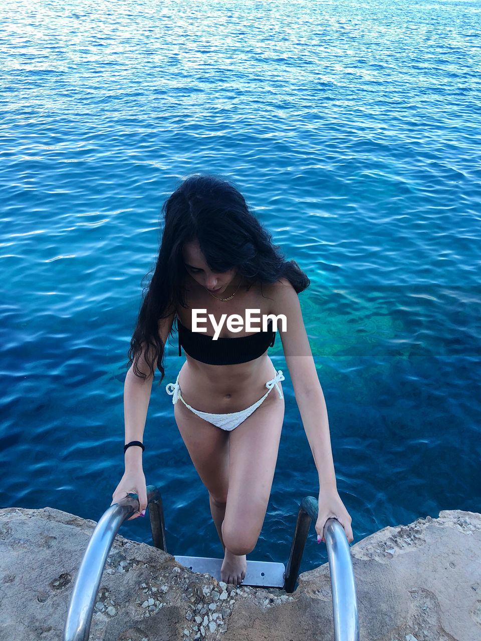 High angle view of woman standing on ladder by sea