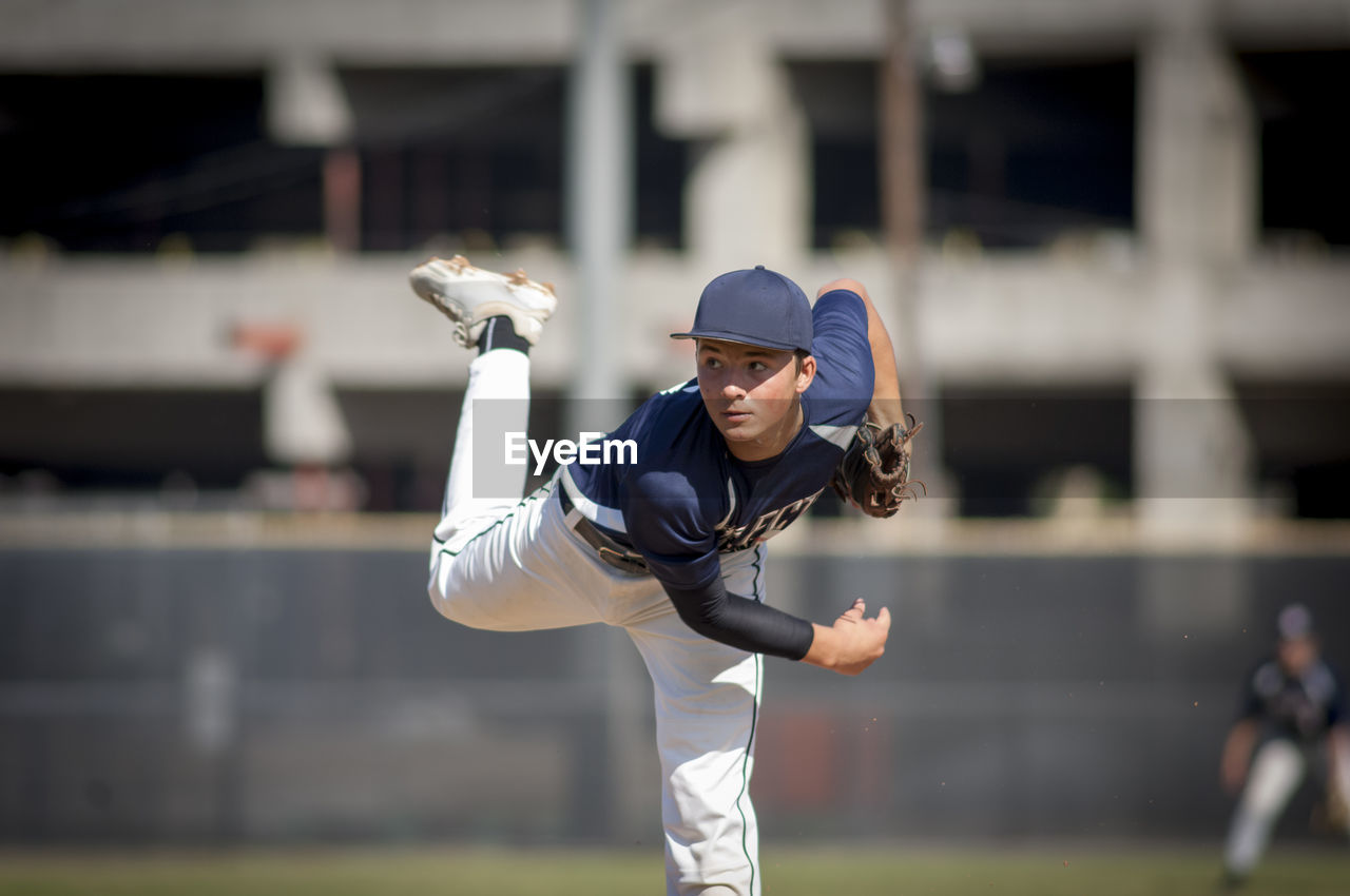 Teen baseball player pitcher in blue uniform on the mound