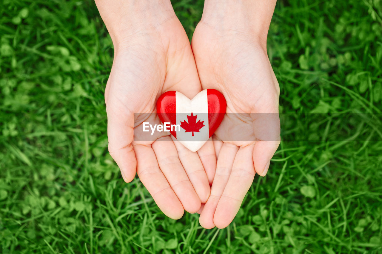 Human hands holding wooden heart with canadian flag symbol. canada day national celebration 