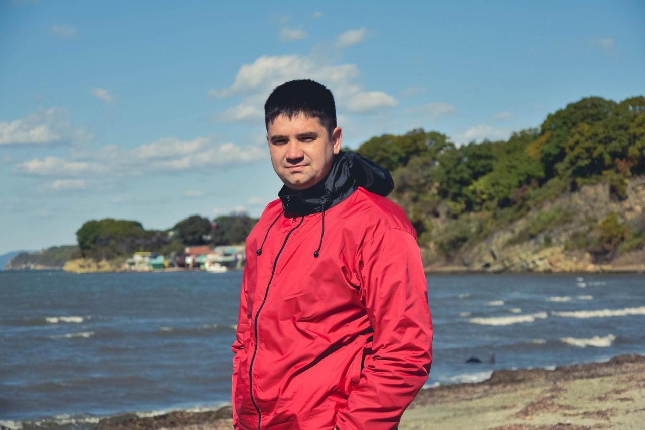 Portrait of man standing at beach against sky