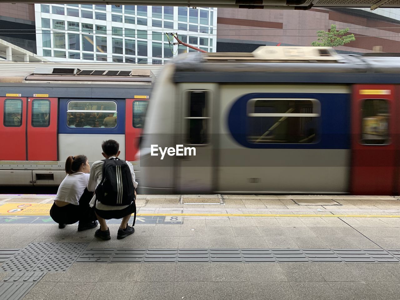 REAR VIEW OF PEOPLE WAITING AT RAILROAD STATION