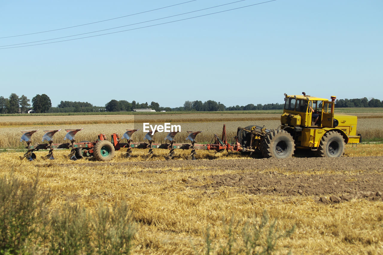 TRACTOR ON AGRICULTURAL FIELD AGAINST CLEAR SKY