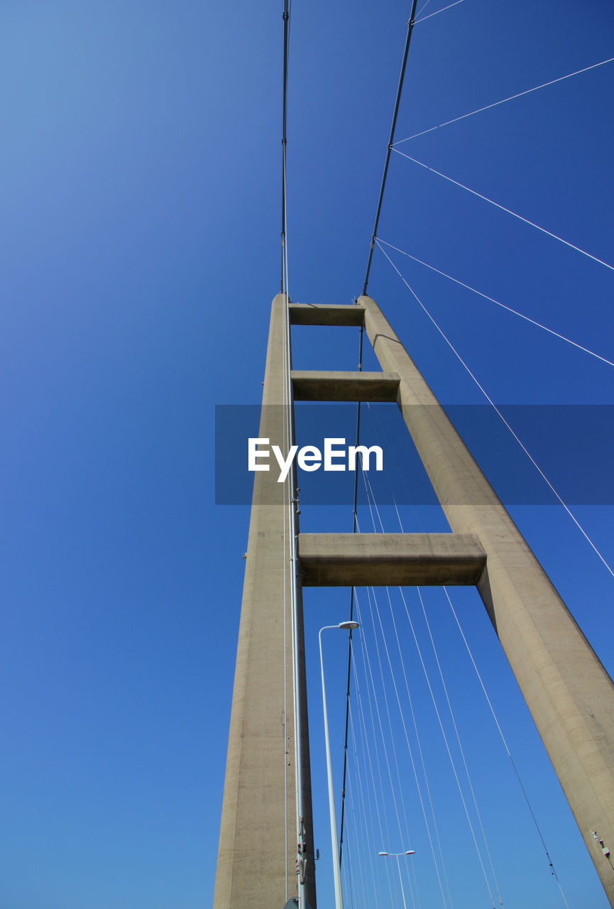 Low angle view of suspension bridge against clear blue sky