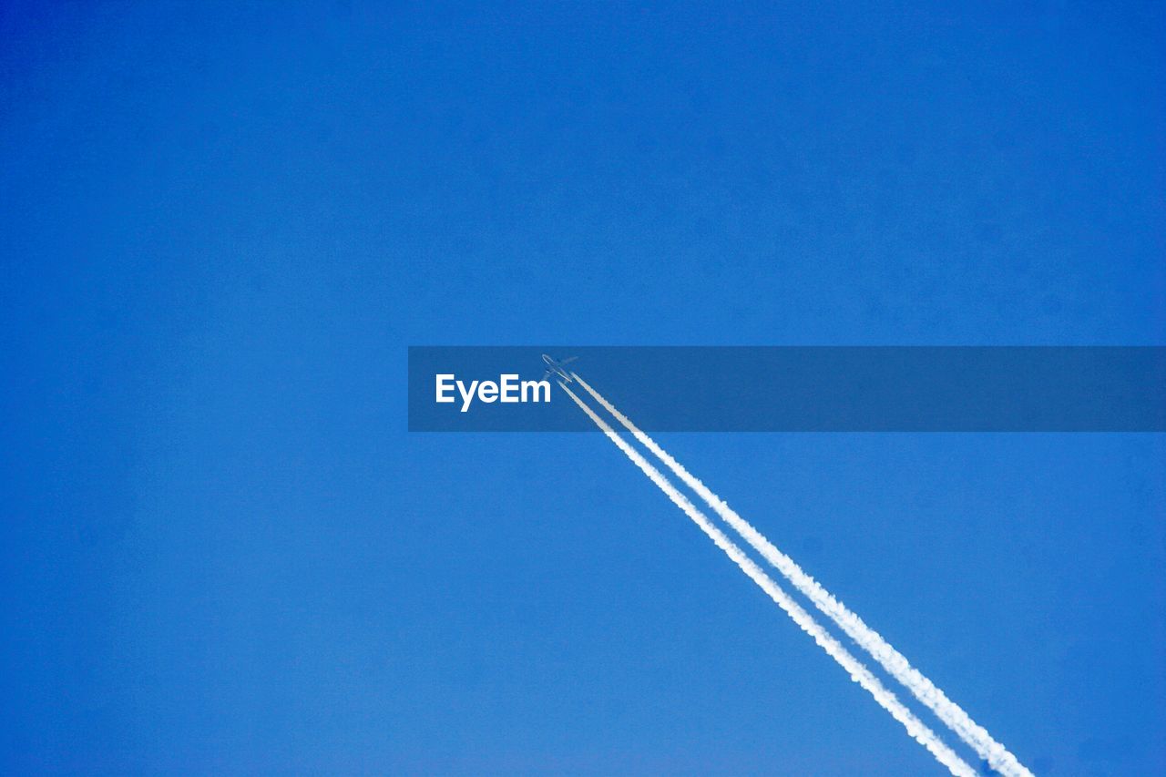 Low angle view of airplane flying against blue sky