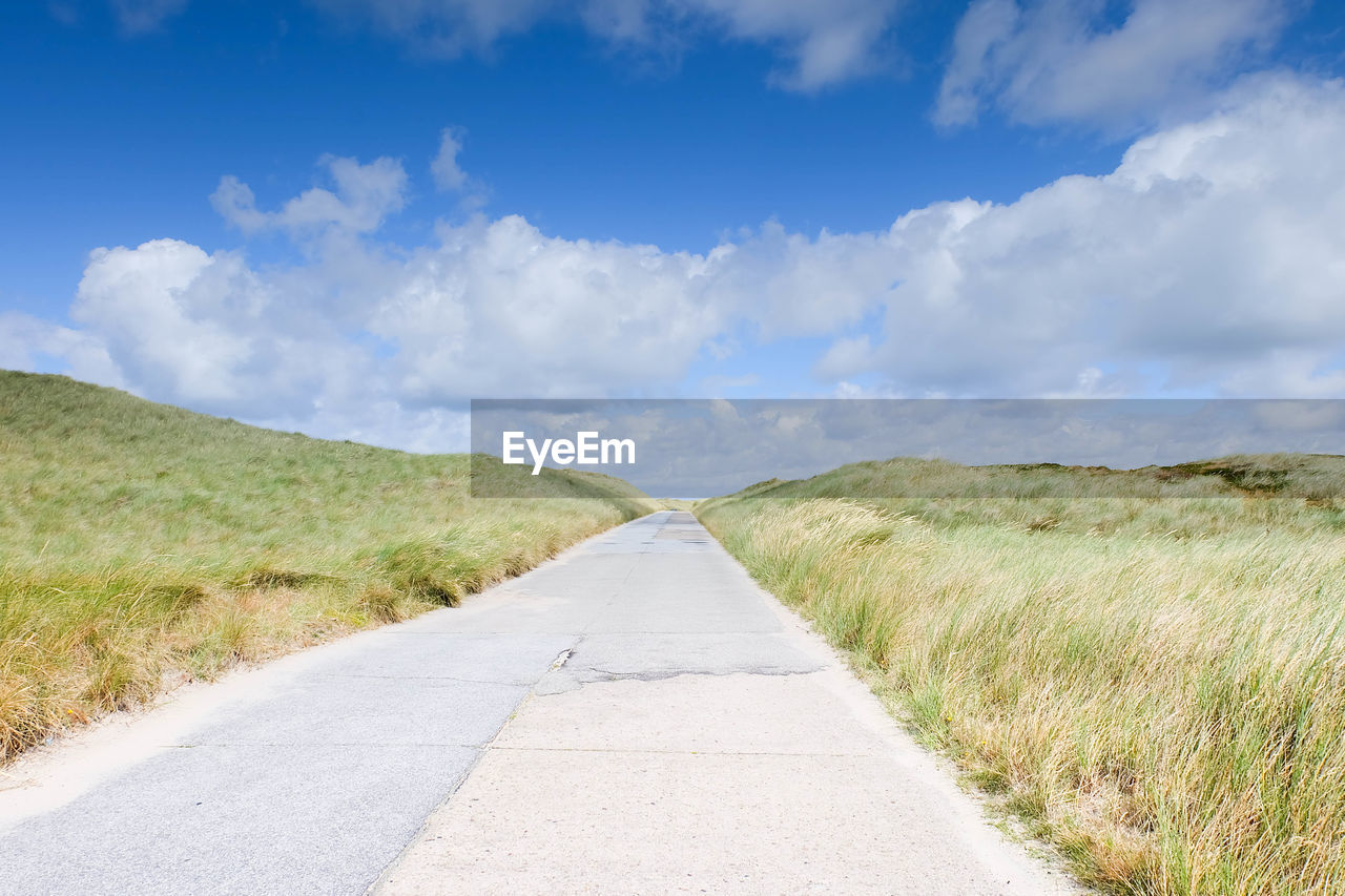 Empty road passing through grassy field