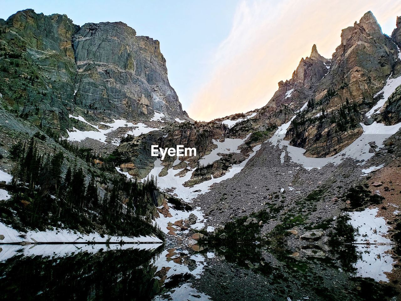 Clear waters of emerald lake as the sun disappears behind hallett peak