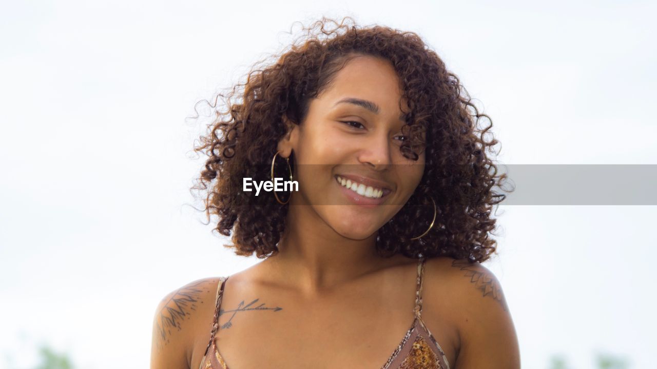 PORTRAIT OF HAPPY WOMAN SMILING AGAINST WHITE BACKGROUND