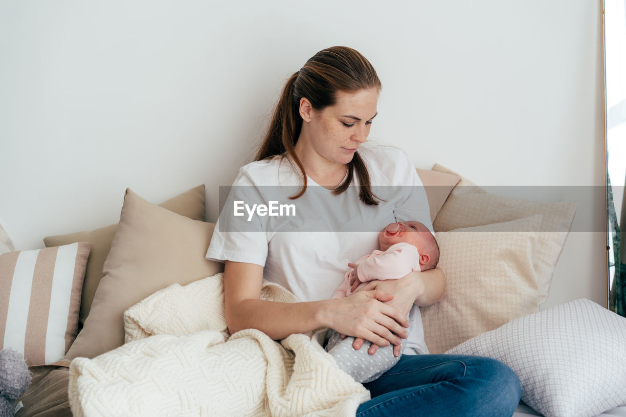 Young caucasian mother with a one-month baby in her arms.