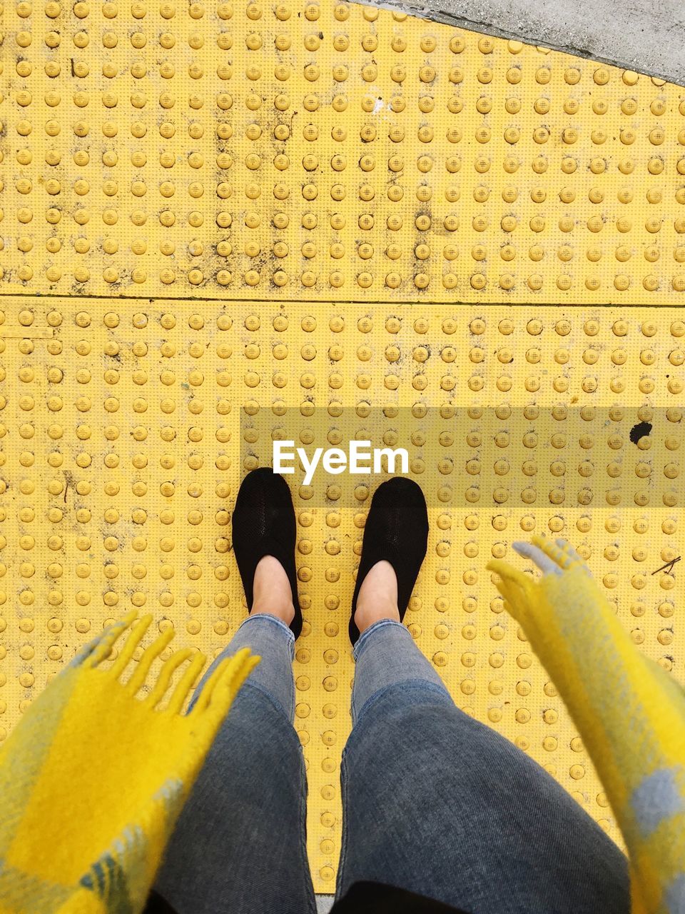 Low section of woman standing on yellow sheet metal