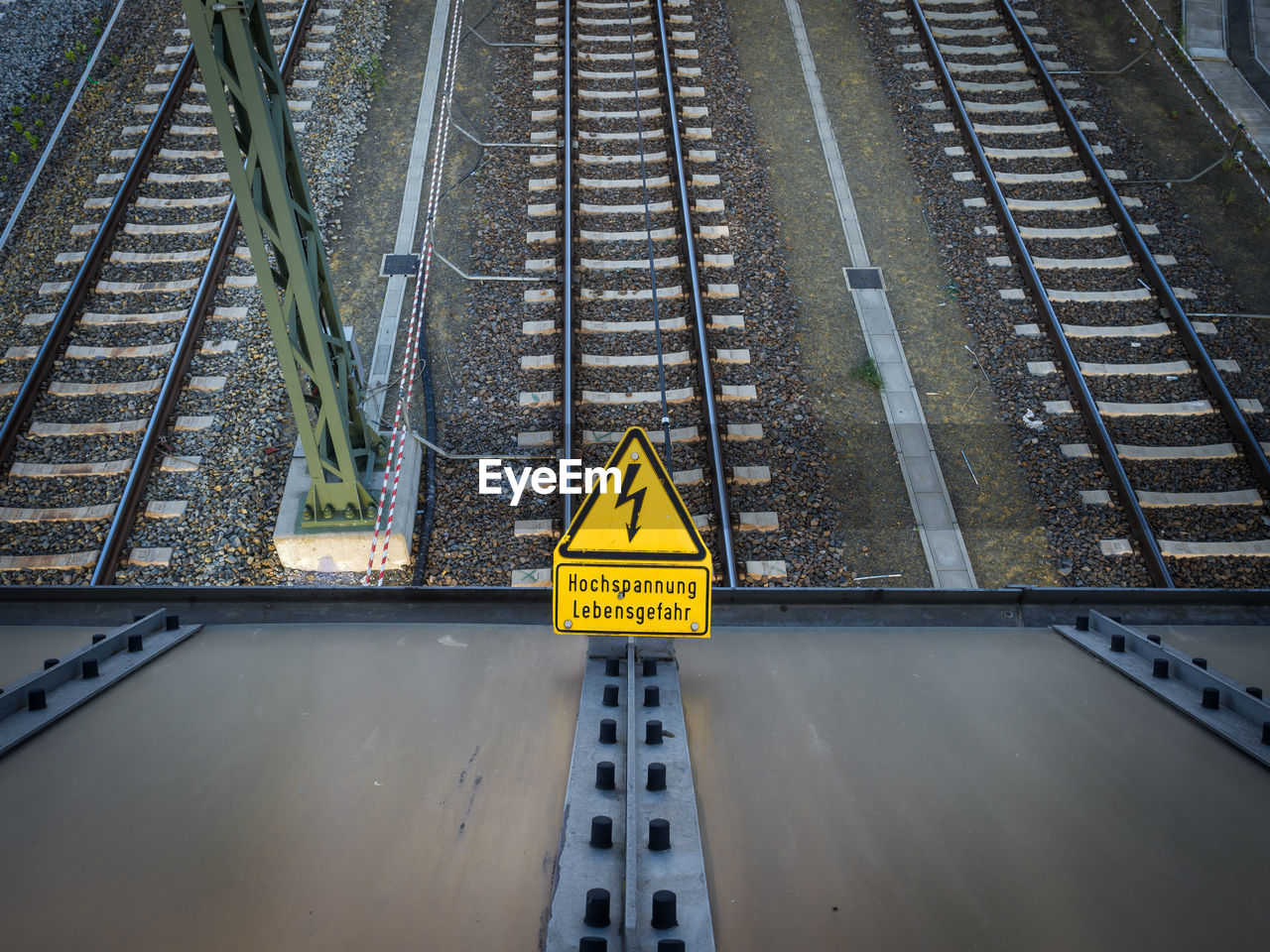 High angle view of high voltage danger sign on railroad tracks