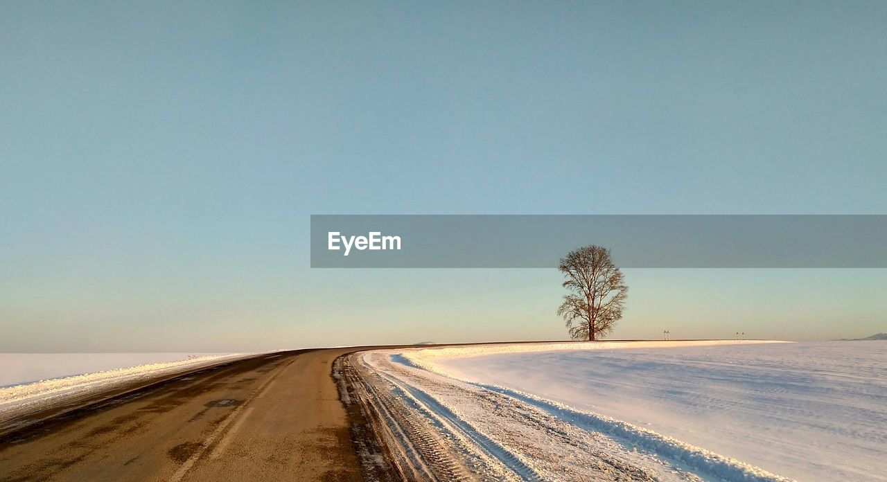 ROAD ON SNOW COVERED LAND AGAINST CLEAR SKY