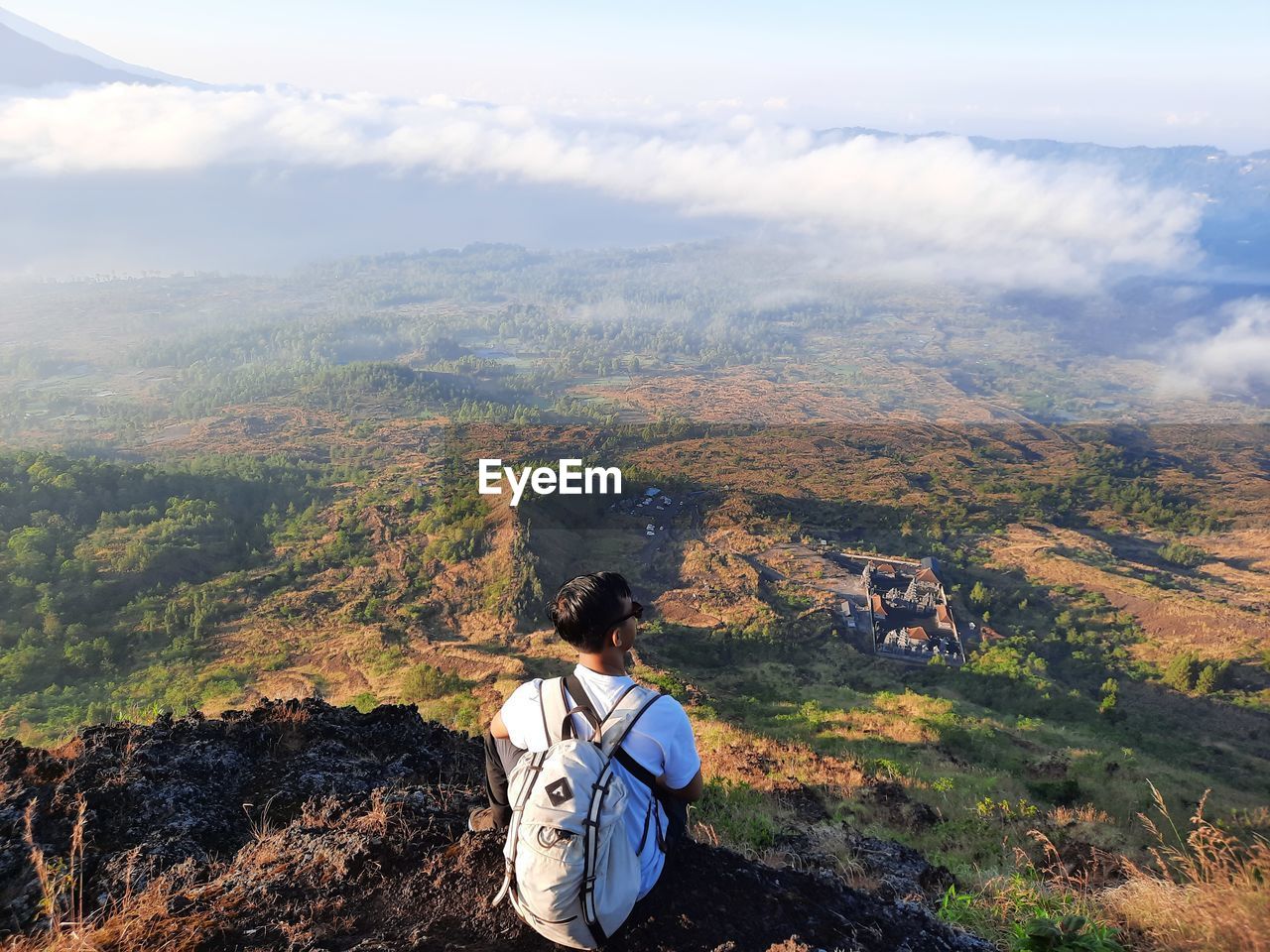 Young man looking at the view from the top of the mountain